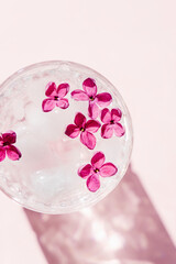 Vivid lilac flowers in glass of water with ice cubes. 