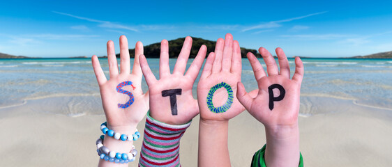 Children Hands Building Colorful English Word Stop. Ocean And Beach As Background