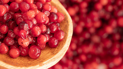 Cranberry placed in a wooden spoon and placed on a wooden floor,  Red sour fruit  There are many health benefits.