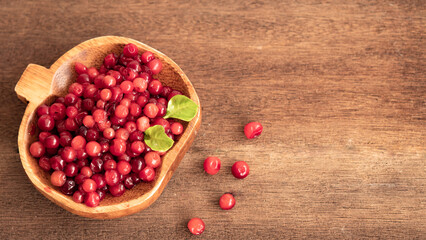 Cranberry placed in a wooden cup and placed on a wooden floor,  Red sour fruit  There are many health benefits.