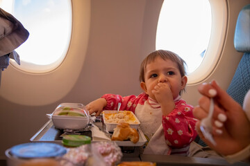 cute infant airplane passenger eats special baby onboard meal diring flight