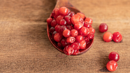 Cranberry placed in a wooden spoon and placed on a wooden floor,  Red sour fruit  There are many health benefits.
