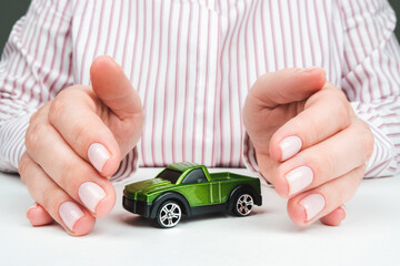 Orenburg, Russia - May 5, 2020: green toy car in female hands, protection and property insurance concept