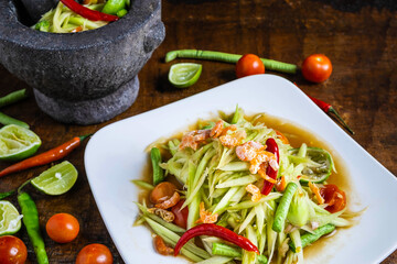 .Cooking Thai food, papaya salad and papaya salad in a dish with a serving on a wooden table.