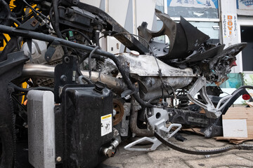 Vehicle, tricycle, after an accident. A burned motorcycle near the workshop. Mechanism metal covered in ashes. Various motorcycle mechanisms are visible. Gears, springs, tanks, skeleton, traction.