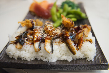 Delicious Asian dinner - boiled rice with grilled fish fillet, soy sauce and vegetables 