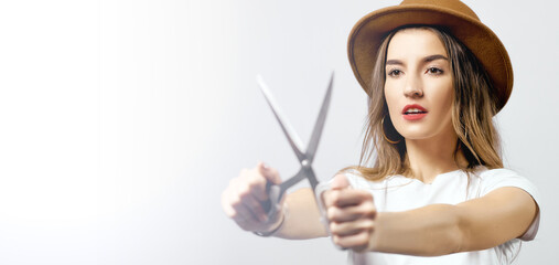 A woman wearing a hat looking through scissors