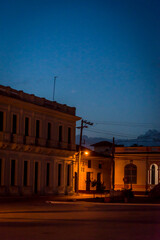 Fototapeta premium Atmospheric Central square with Spanish colonial style buildings and illuminated street lamp, Remedios, Cuba