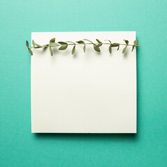 White memo pad, empty paper with eucalyptus leaves on mint green background. top view, copy space