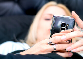 Blonde woman using her mobile phone in the bed