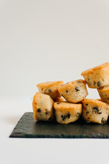 Chocolate chips little muffins in a dark slate board plate isolated on white. Vertical photo. Muffin, sweet and food concept.