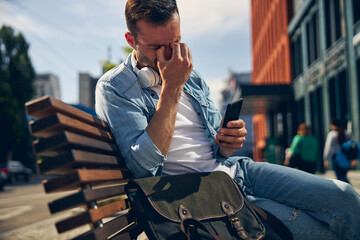 Tired young male person pressing his eyes
