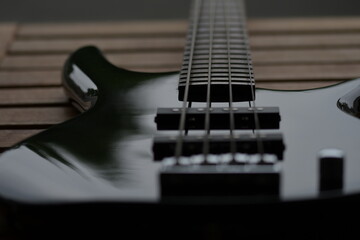 Eine schwarze E Bass Gitarre von unten fotografiert. Man sieht ein Teil des Korpus, der Seiten und...
