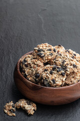 Healthy protein granola crackers with raisins and nuts on black stone background