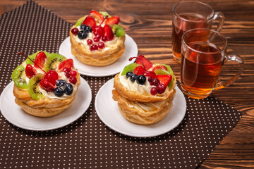 Home made cake with cream and fruit and hot tea on wooden table.