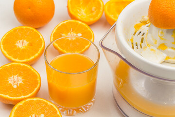 Half orange on juicer. Glass of juice, oranges closeup. Cooking Orange Juice.