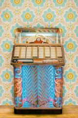 Colorful vintage jukebox in front of retro flower wallpaper on a wooden floor