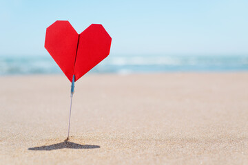 red origami heart on the beach