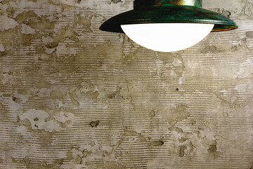 An empty concrete wall with space for text, lit by a lamp above.