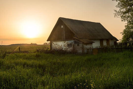 Old rural barn in a field at sunset. Vintage photo of a rustic house. Ukraine.