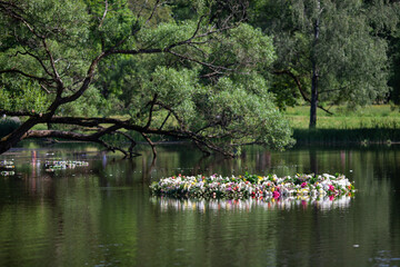 Beautiful  huge wreath of fresh flowers on the water. The celebration of Ivan Kupala (St. John Day). Old holiday dedicated to the summer solstice. Selective focus.