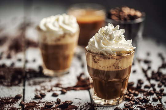 Black coffee with whipped cream in glass cups and spilled coffee beans