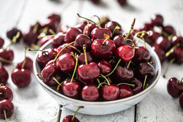 Fresh cherries washed in clean water in a bowl and scattered all around