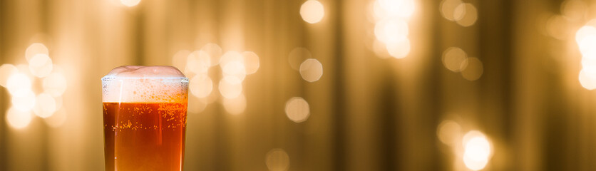 light beer in a figured glass on a black table on a blurred background