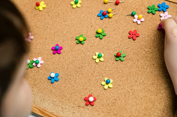 Flower meadow. Kids making flowers from wooden buttons and push pins on cork pin board. Therapeutic exercise for fine motoric skills and concentration of attention.