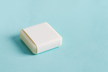 Handmade herbal natural soap bar with paper label on a pastel blue background. Mock-up for your design and creativity.