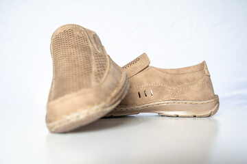 Men's beige leather shoes, models moccasins. Photographed close-up on a light background.