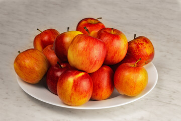 Red apples are on a white plate. Close up