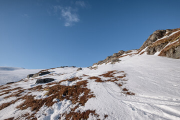 Snowy hill with rocks and blue sky in alpine on winter