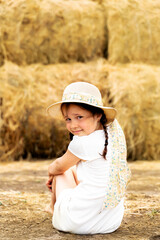 beautiful cheerful little girl in a straw hat on the hay