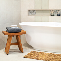 Serene inviting freestanding bath with wooden stool and lit candles