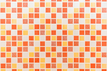 Multiple colored square mosaic tiles texture with white filling decorate the wall in the bathroom.