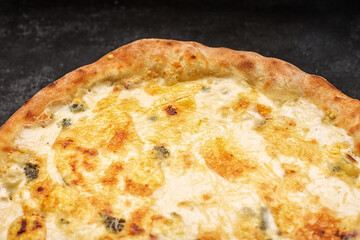 Four cheese pizza on a light wooden board, on a dark concrete background