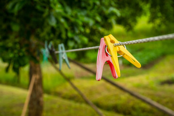 multicolored clothespins on a rope in the garden on a blurred garden background.