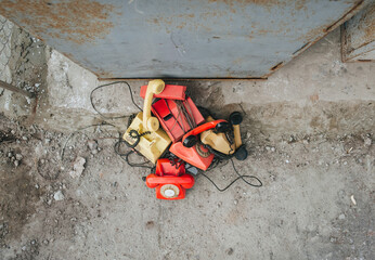 Many multi-colored old, discarded, unnecessary phones stand near a metal urn waiting for recycling....