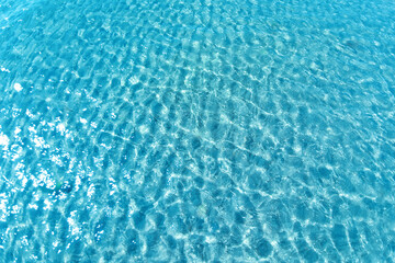 Background shot of aqua water surface. Swimming pool with sunny reflections.