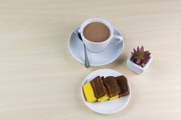 Morning breakfast with a cup of milk tea and layer cakes isolated on a wooden background.