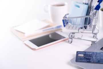 Office online paying, stay home shopping, electronic payment with credit card concept, laptop on white table background with shop cart, close up.