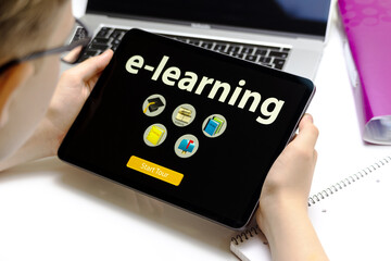 Schulkind hält ein Tablet in den Händen mit dem TEXT E-LEARNING