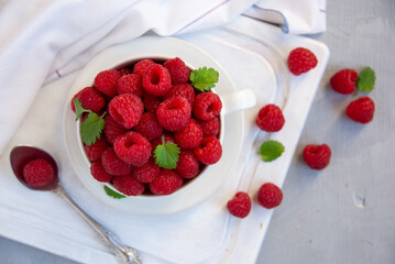 Fresh raspberries with leaves in white cup