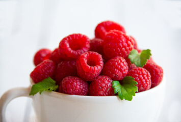 Fresh raspberries with leaves in white cup