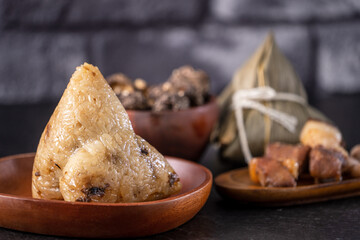 Rice dumpling, zongzi - Chinese rice dumpling zongzi on black brick background slate table, concept of Dragon Boat Festival traditional food, close up.
