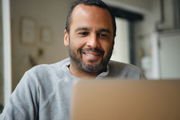Close up smiling businessman happily working on laptop during coffee break in cafe