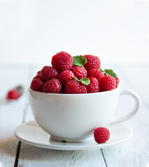 Fresh raspberries with leaves in white cup