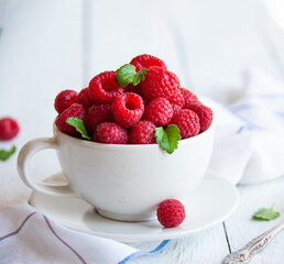 Fresh raspberries with leaves in white cup