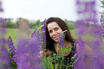 Girl sitting in a meadow. Among the blooming lupine.